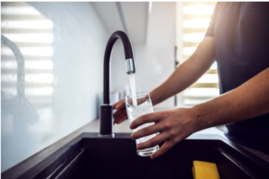 man-hand-filling-glass-of-water-from-kitchen-sink